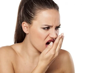 Mujer sorprendida con una mano en la boca 
                        percibiendo su mal aliento (halitosis)